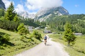 Thumbnail image of cyclists approaching the Seebenalm restaurant with the Sonnenspitze mountain behind in the Mieminger