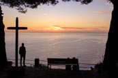 Thumbnail image of man viewing the sunset view of the coast by a cross from Riomaggiore, Cinque Terre, Liguria, Italy